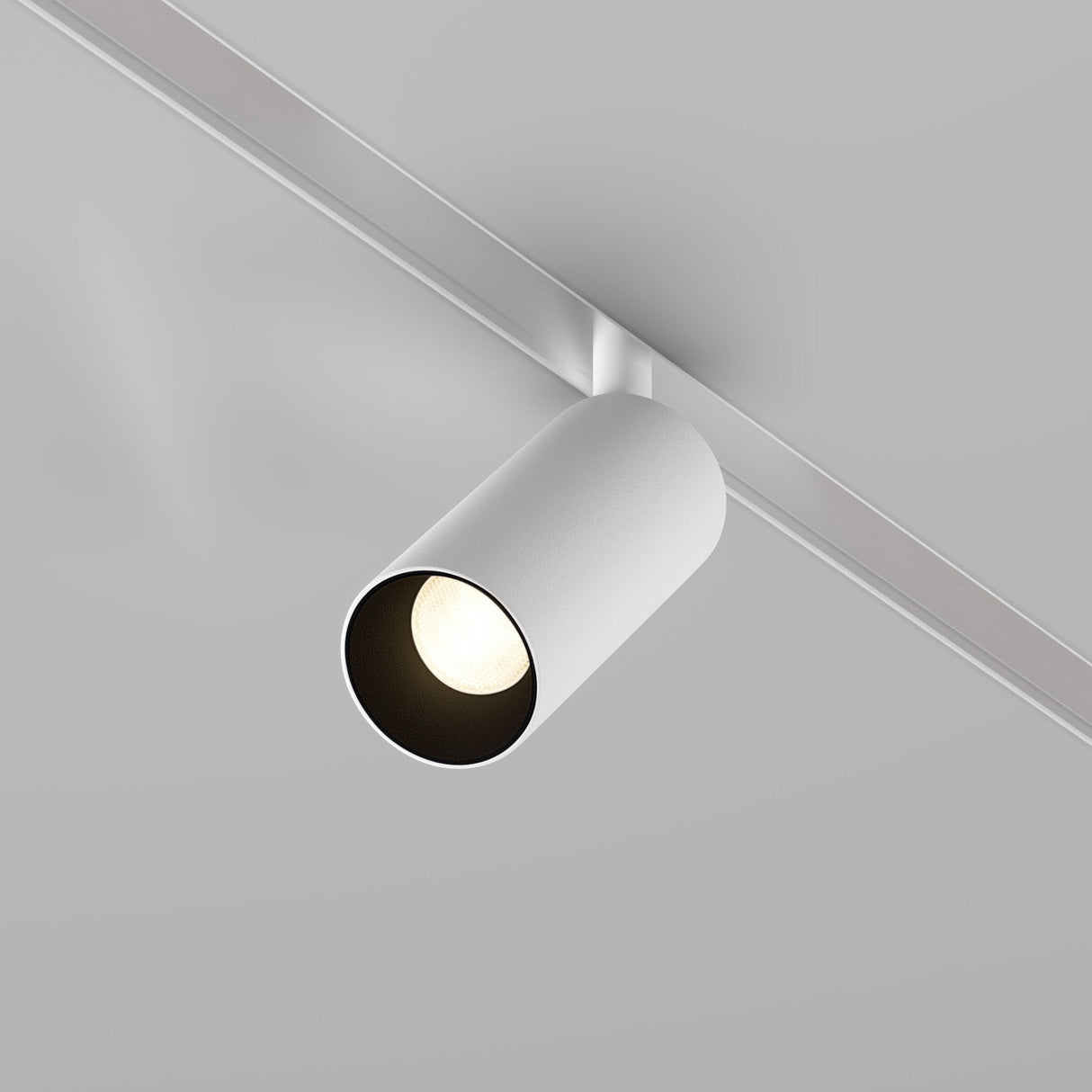 The Focus LED CCT Magnetic Exility Track Spotlight 5W 2700-6000K in white casts a focused beam downward. This energy-efficient cylindrical fixture mounts on a sleek, metallic track against the grey ceiling.