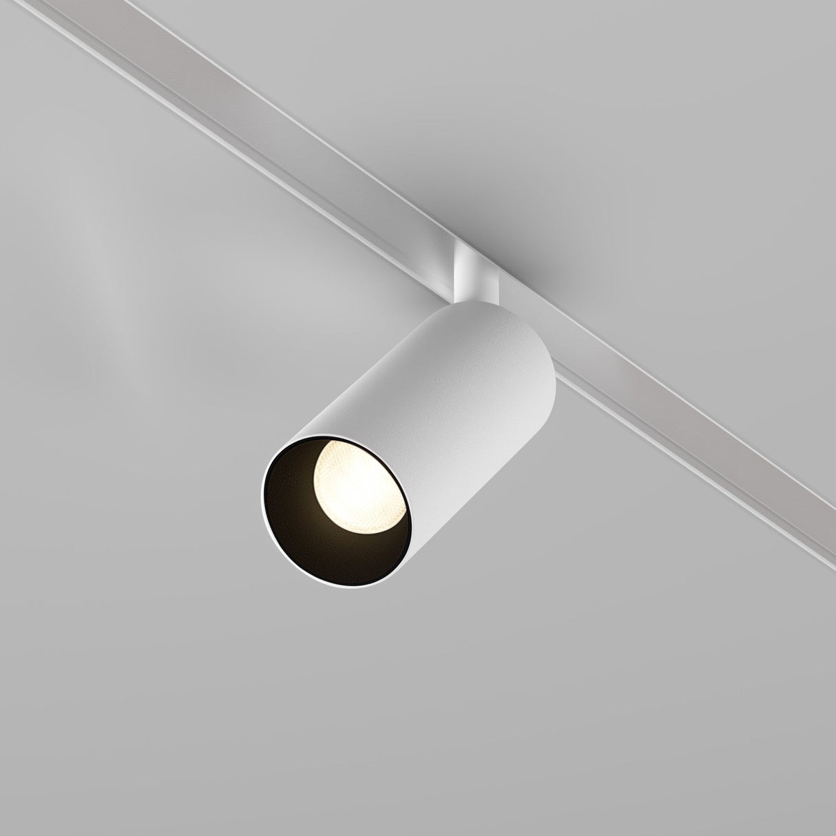 The Focus LED DALI CCT Magnetic Exility Track Spotlight 5W 2700-6000K in white, featuring a minimalist design, casts light downward from a plain light gray ceiling. It emphasizes modernity and seamlessly integrates with the magnetic track system.