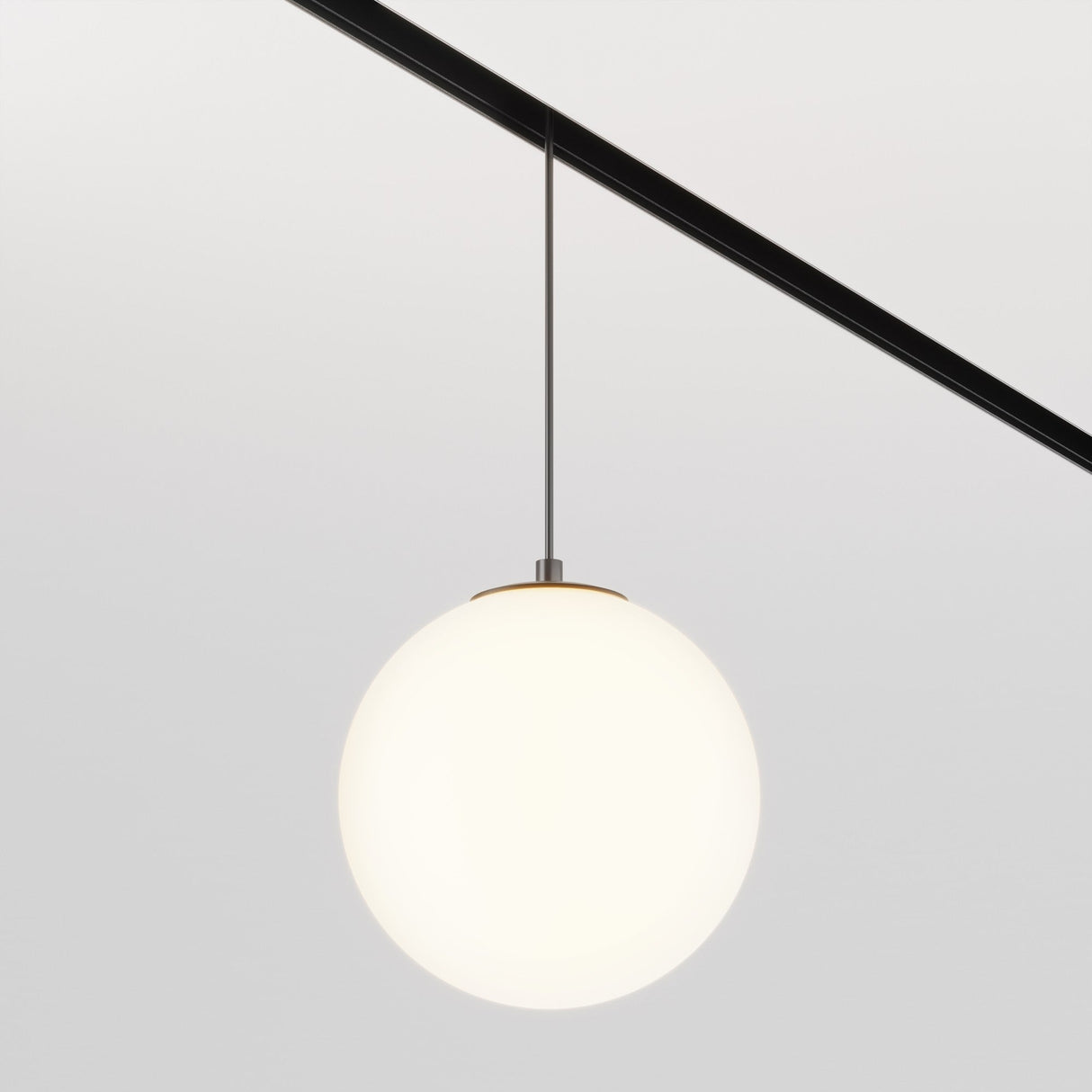 The Luna LED Exility Magnetic Track Pendant Light 5W 3000K - Black showcases a round, frosted glass globe on a sleek dark rod, casting ambient light on a plain, light gray wall to highlight its minimalistic design.