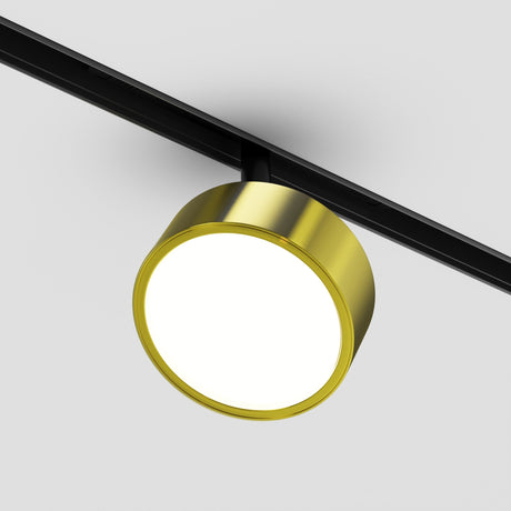 A Rado 18W CCT LED Dimmable Magnetic Exility Track Spotlight, featuring a black track and brass finish, is mounted on a white ceiling. It emits an adjustable bright glow with smart tech features, reflecting minimalistic modern design.