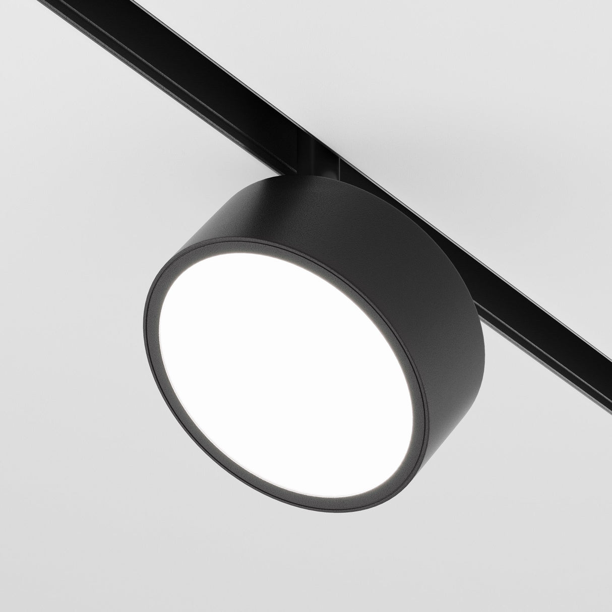 A close-up view of the sleek Rado DALI CCT LED Dimmable Magnetic Exility Track Spotlight 18W in black, emitting a bright white light. It is mounted on a plain white background, ideal for adjustable lighting needs between 2700-6000K.