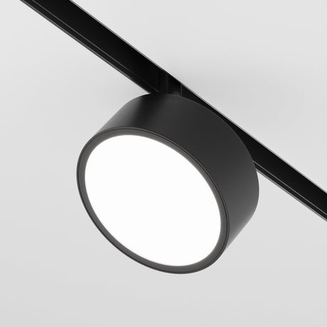 A close-up view of the sleek Rado DALI CCT LED Dimmable Magnetic Exility Track Spotlight 18W in black, emitting a bright white light. It is mounted on a plain white background, ideal for adjustable lighting needs between 2700-6000K.