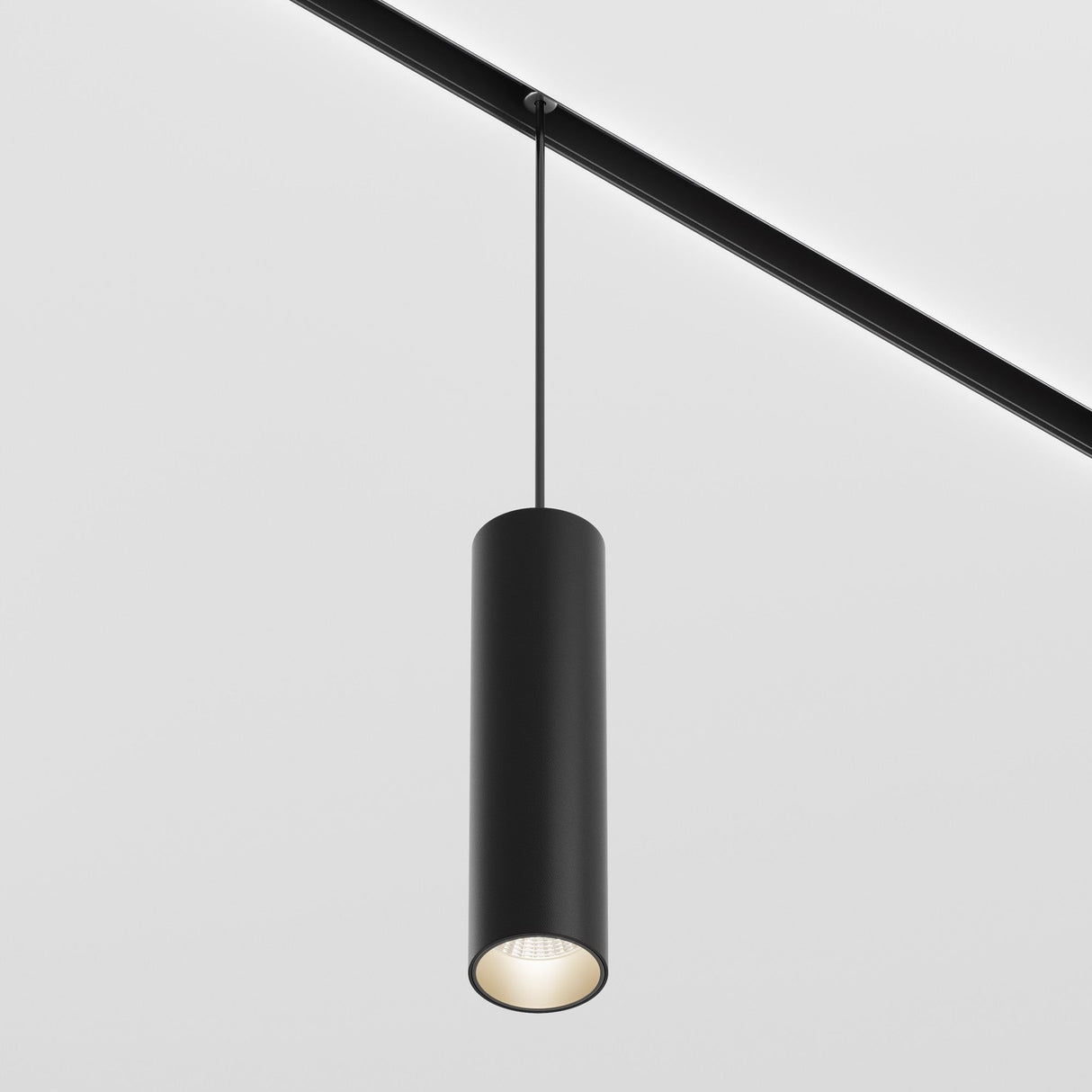 The Focus LED CCT DALI Dimmable Exility Magnetic Track Pendant Light 12W (2700-6000K) in Black offers a sleek, cylindrical design. It softly illuminates downward with modern charm on a plain white background, featuring DALI dimming technology for adjustable lighting.