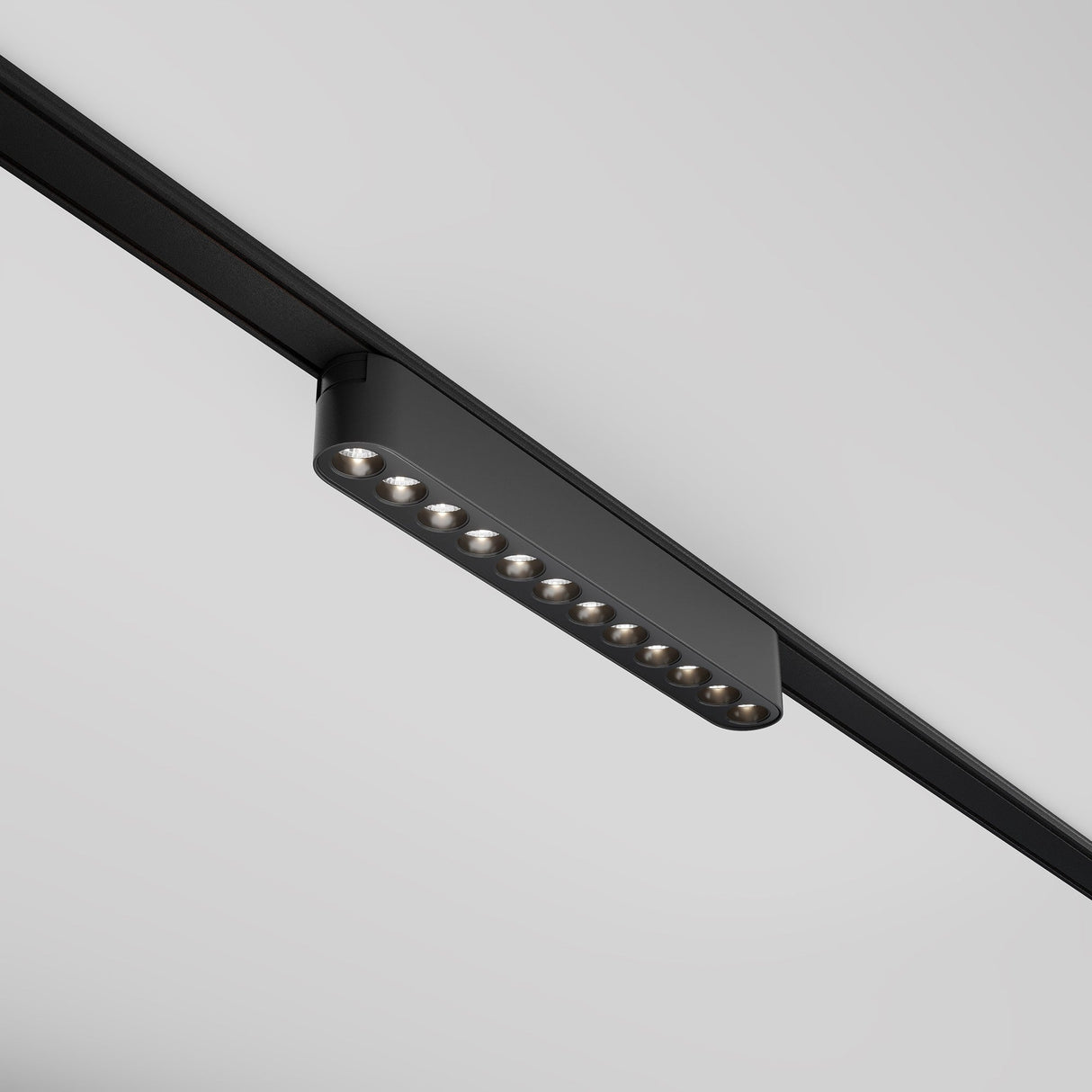 The Points LED Linear Track Light for Magnetic Tracks Radity, 12W and 4000K in black, is mounted on a gray ceiling. With nine individual lights, it casts a modern, minimalist appearance.