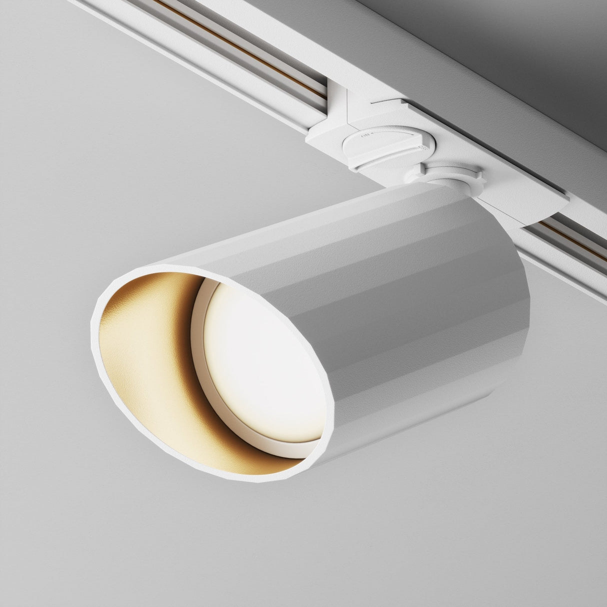 The Lipari Single Phase Unity Track Spotlight in white features a minimalist ceiling-mounted design with a cylindrical light fixture and luxurious gold interior. Its attached to an adjustable track system and is currently switched off against a neutral gray background.