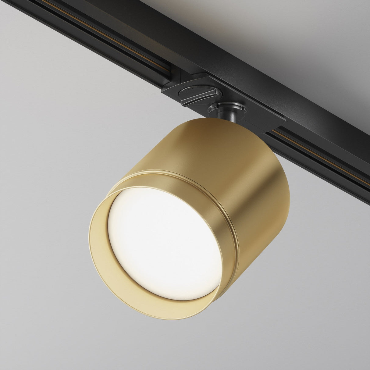 Close-up of the Polar LED Single Phase Unity Track Spotlight in Matte Gold, attached to a black ceiling rail. The illuminated fixture provides sleek luxury accent lighting ideal for modern interiors.