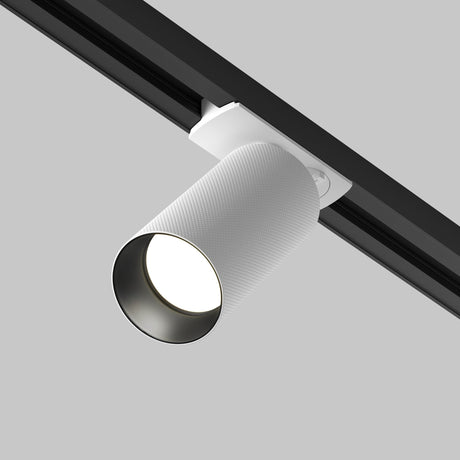 Close-up of the Artisan Unity Spotlight in white on a black rail, angled downward against a gray backdrop. The single-phase fixture features a modern design and ribbed texture, making it ideal for enhancing contemporary interiors.