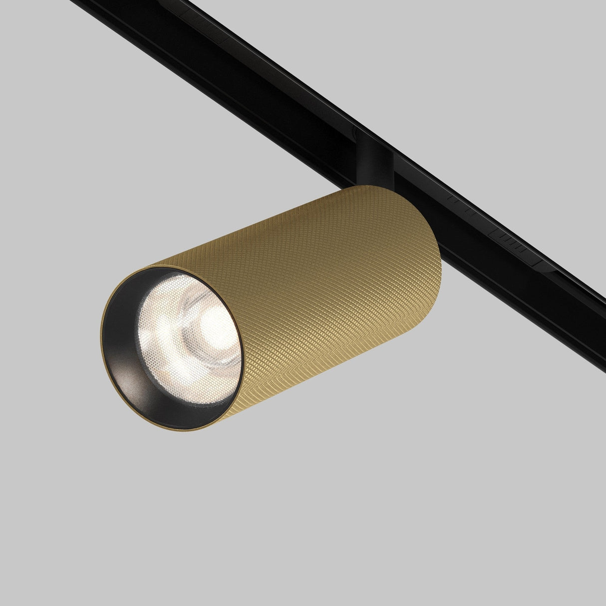 A cylindrical gold-textured light fixture on a black track contrasts with a gray background, featuring the Artisan LED Magnetic Exility Track Spotlight emitting white light via an anti-glare filter, showcasing modern energy efficiency.