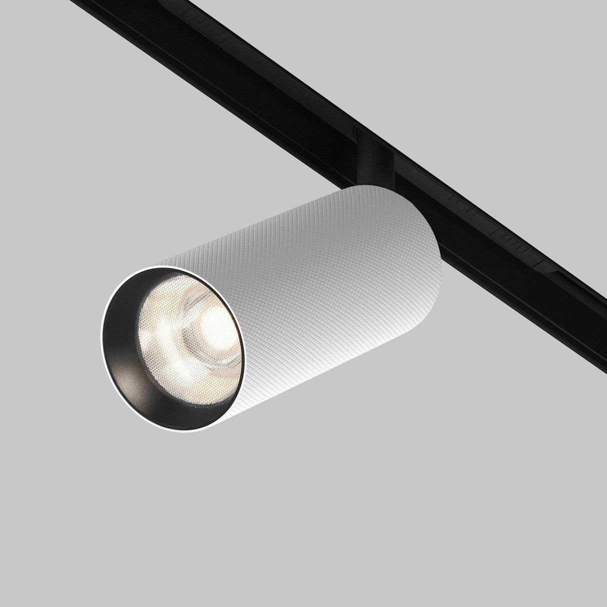 A white, cylindrical Artisan LED Magnetic Exility Track Spotlight 12W 4000K with a textured surface and anti-glare filter is mounted on a black rail against a gray background, casting a soft glow.