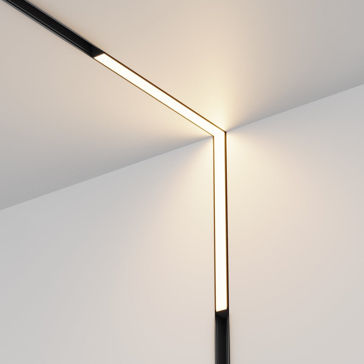 The minimalist corner features the Basis LED 90° Linear Track Lights for Magnetic Exility, with a black finish that highlights their soft, warm glow. These sleek lights accentuate the modern design against clean, white walls.