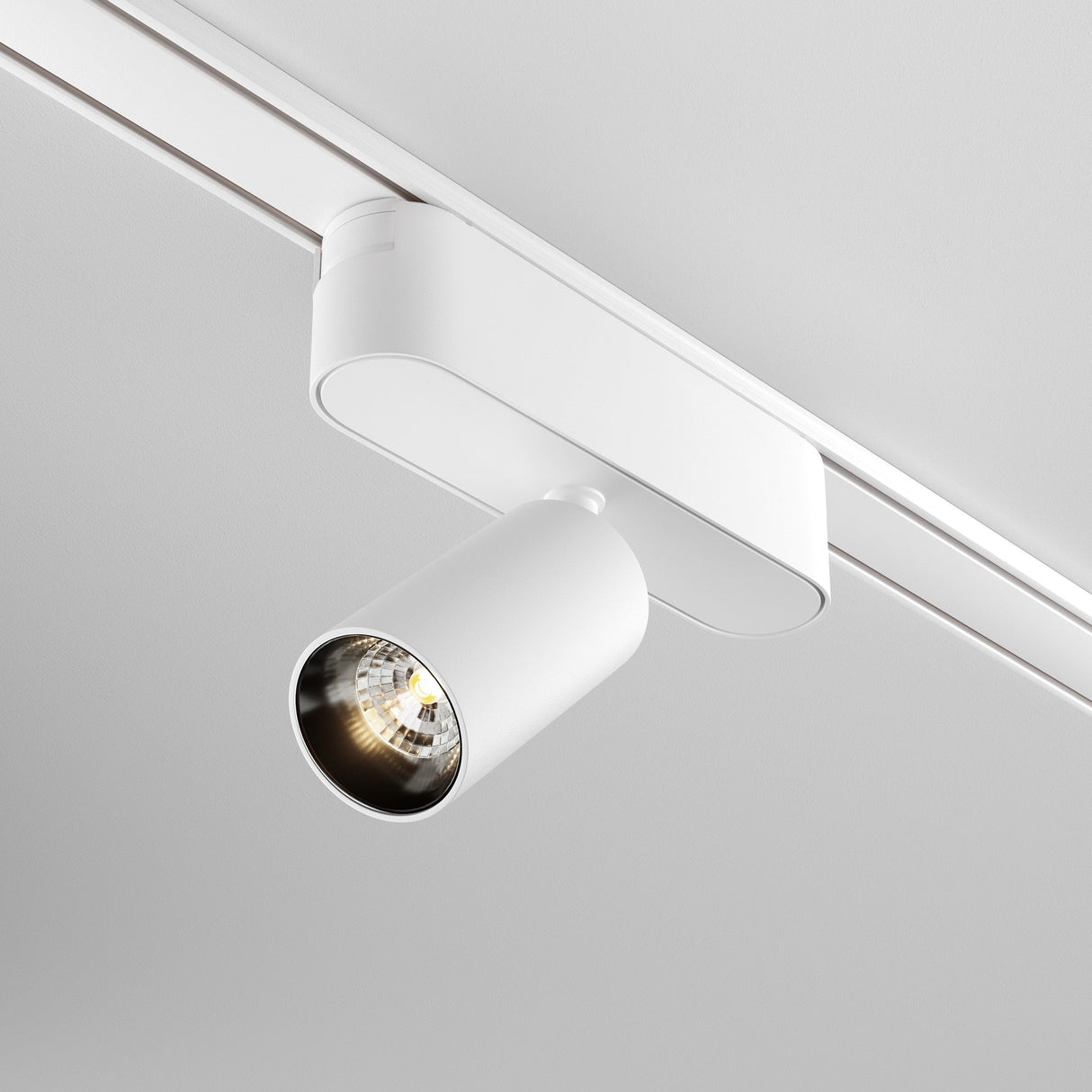 The Focus LED Magnetic Radity Track Spotlight 5W 3000K in white is ceiling-mounted, casting a focused beam from its cylindrical design. Its linear track matches the ceiling color, providing sleek accent lighting.