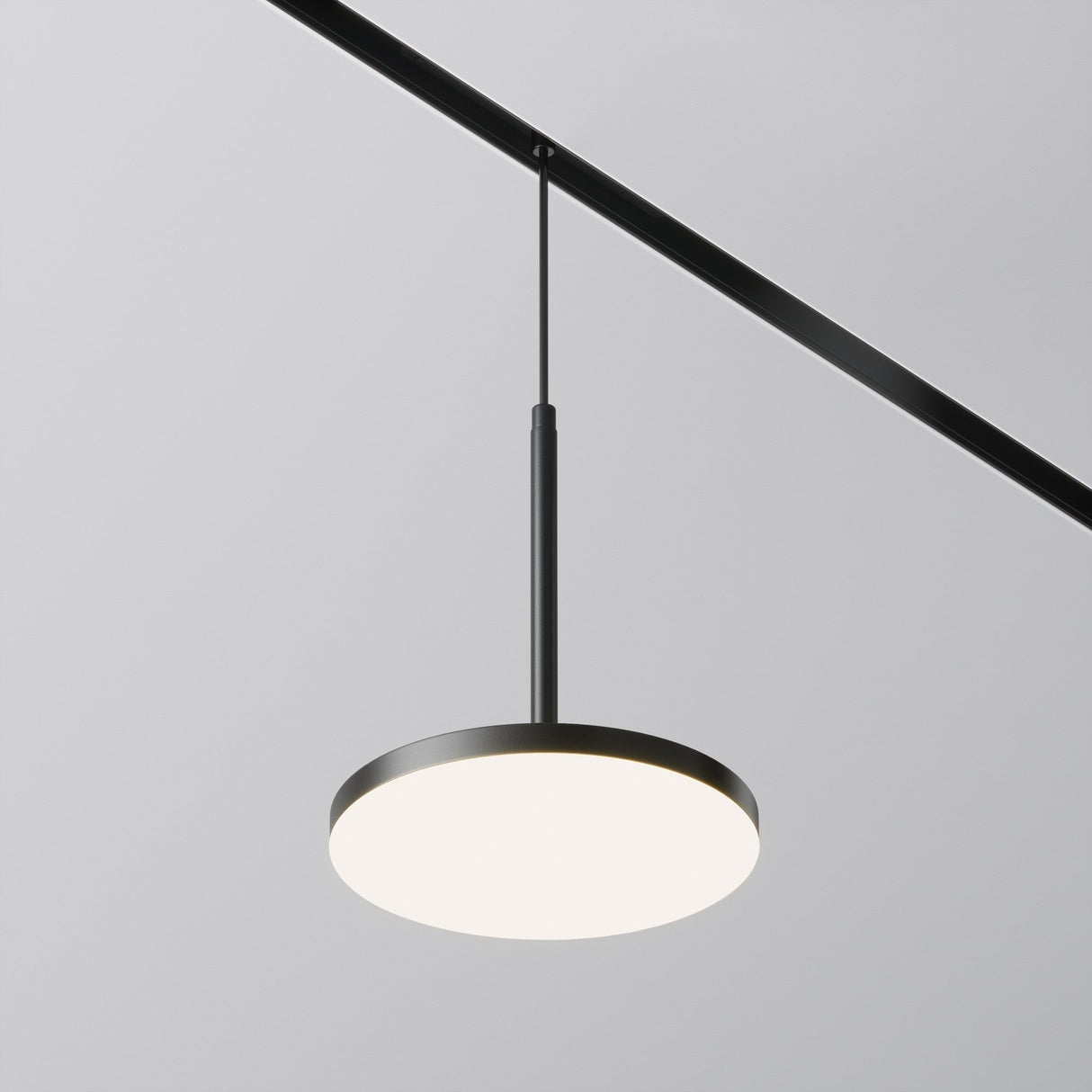 The Plato CCT LED Dimmable Magnetic Exility Track Pendant Light in black offers a modern circular design. It provides a soft white glow with adjustable color temperatures from 2700-6000K, perfect for any ambiance, and is suspended from a magnetic track system on the ceiling.