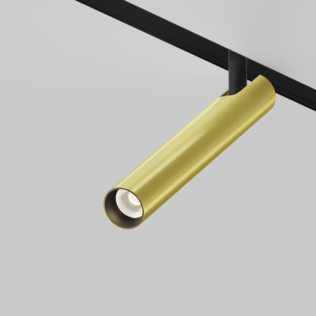A sleek, cylindrical gold track light fixture resembling the Focus T LED Magnetic Exility Track Spotlight 6W 3000K - Black & Brass is mounted on a black track against a light gray ceiling. The lamp is angled slightly downward, highlighting its minimalist and modern design.