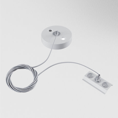 The Unity Single Phase Surface-Mounted Track Suspension Cable - White features a ceiling-mounted cable fixture with a round base, coiled wire, and three circular elements connected to a rectangular component, creating a sleek modern suspension setup on a plain white background.