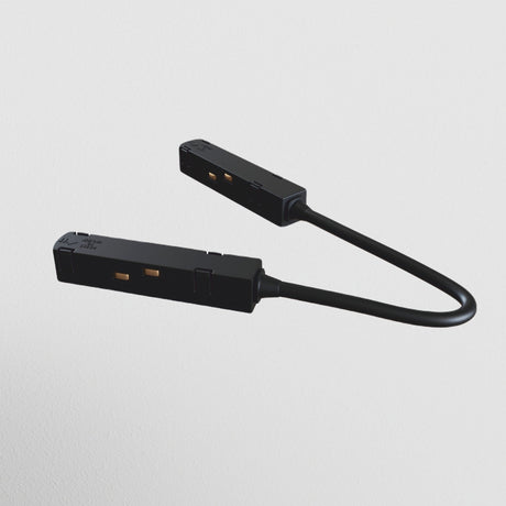 The S35 Track Corner Power Connector - Black, set against a plain white background, features two slender connectors linked by a flexible cable resembling plug prongs. Its essential for any lighting layout using the S35 magnetic track system.