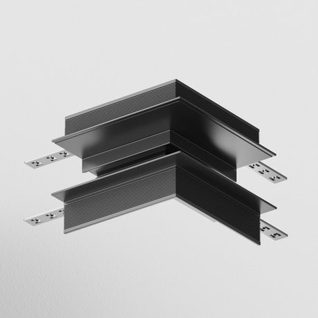 The S35 Tracks Recessed L-Shape External Corner Connector in black is a minimalist two-tier ceiling mount with sleek lines and metallic accents. Its recessed design is perfect for suspension from light gray ceilings, highlighting modern elements and contrasting textures.