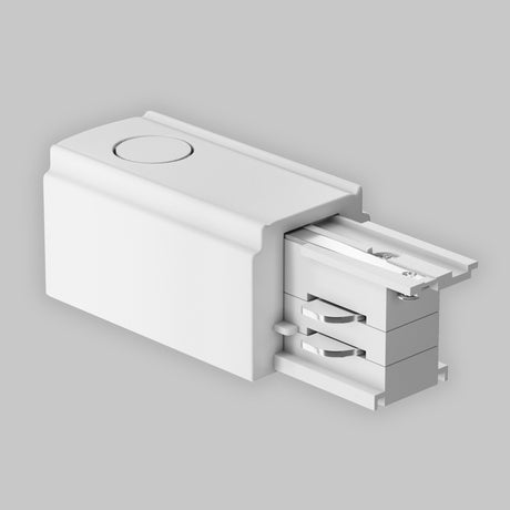 The 3-Phase Track Trinity Left Power Input in white features a sleek, rectangular design on a light gray background. Made from durable plastic, it has a circular indentation on top and visible metallic contact for efficient three-phase track lighting connection.