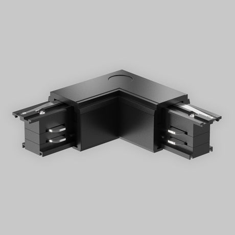 The 3-Phase Surface-Mounted Track Trinity Left Corner Connector External in black is an L-shaped piece with two open ends, designed for three-phase track lighting. It features a smooth finish and visible metallic connectors on each side, set against a plain gray background.