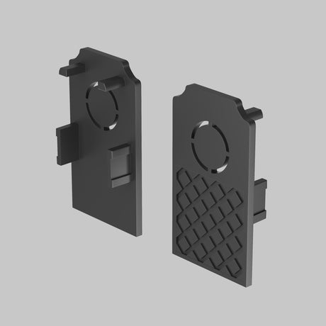 The Exility End Cap 2-Pack for Built-in Tracks - Black showcases sleek design with two black plastic components featuring geometric holes and textured surfaces. Left piece is smooth; right has a grid pattern. Both have rectangular protrusions and a top circular indentation on a light gray background.