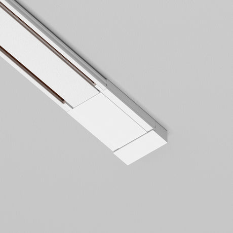 The Radity Magnetic Track Surface Power Feed - White is a modern rectangular ceiling light that features clean lines and a minimalist design, offering a contemporary flair ideal for enhancing modern interiors on a gray ceiling.