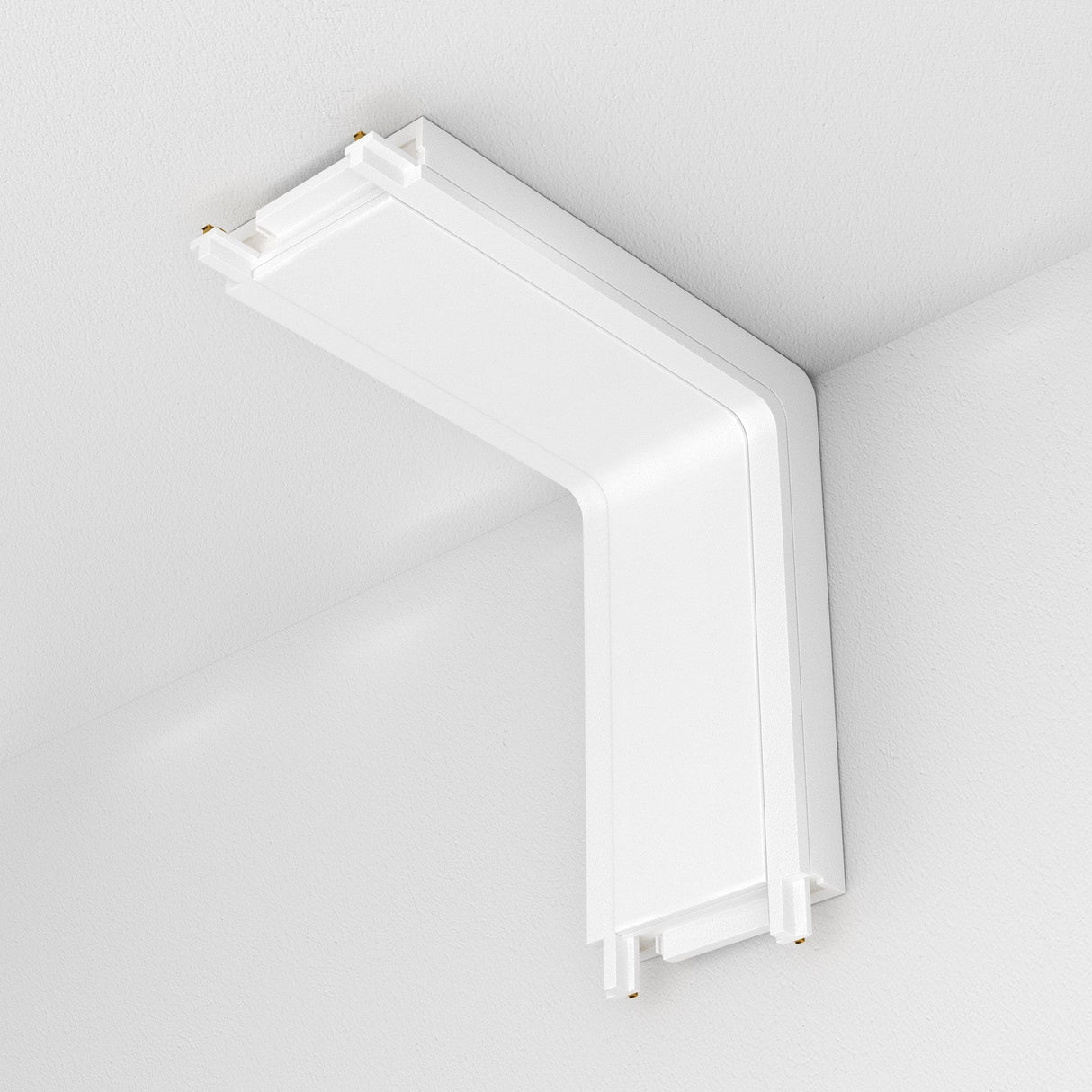The Radity Magnetic Track Power Connector Internal in white is an L-shaped ceiling fixture with a modern design, featuring smooth lines and a minimalist look. It is mounted against a white ceiling and includes an integrated magnetic track system for versatile lighting arrangements.