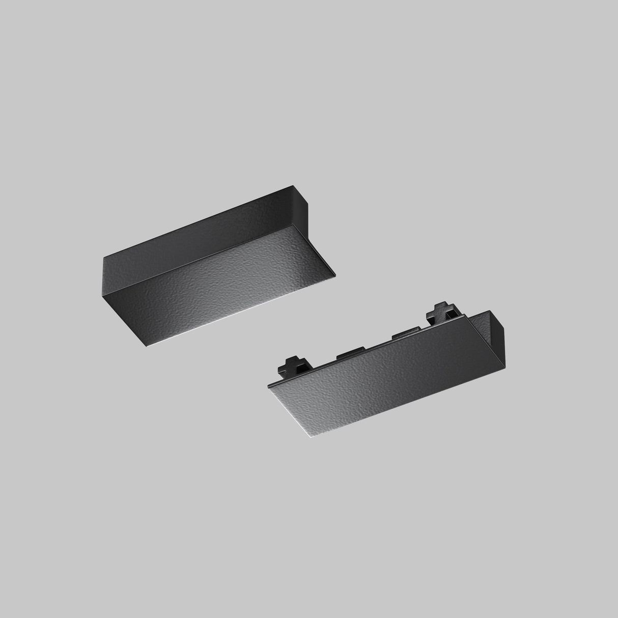 Two Radity magnetic surface-mounted track end caps in black hover gracefully against a gray background, with the top cap sloped for a sleek look, complementing the rectangular one with a studded design below.