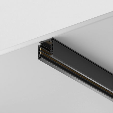Close-up of the black Trinity Three Phase Surface-Mounted Track 2m, installed flush with a white ceiling. It features multiple parallel channels for adjustable fixtures on a three-phase track system.