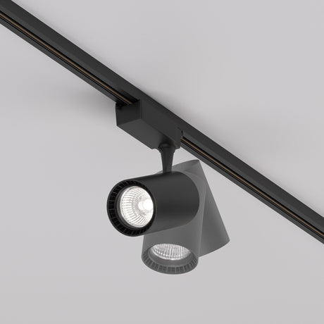 A black Vuoro S LED Single Phase Unity Track Spotlight 26W 4000K is mounted on the light gray ceiling, featuring two cylindrical lights. One beam shines brightly at 4000K and CRI 90, while the other is off.