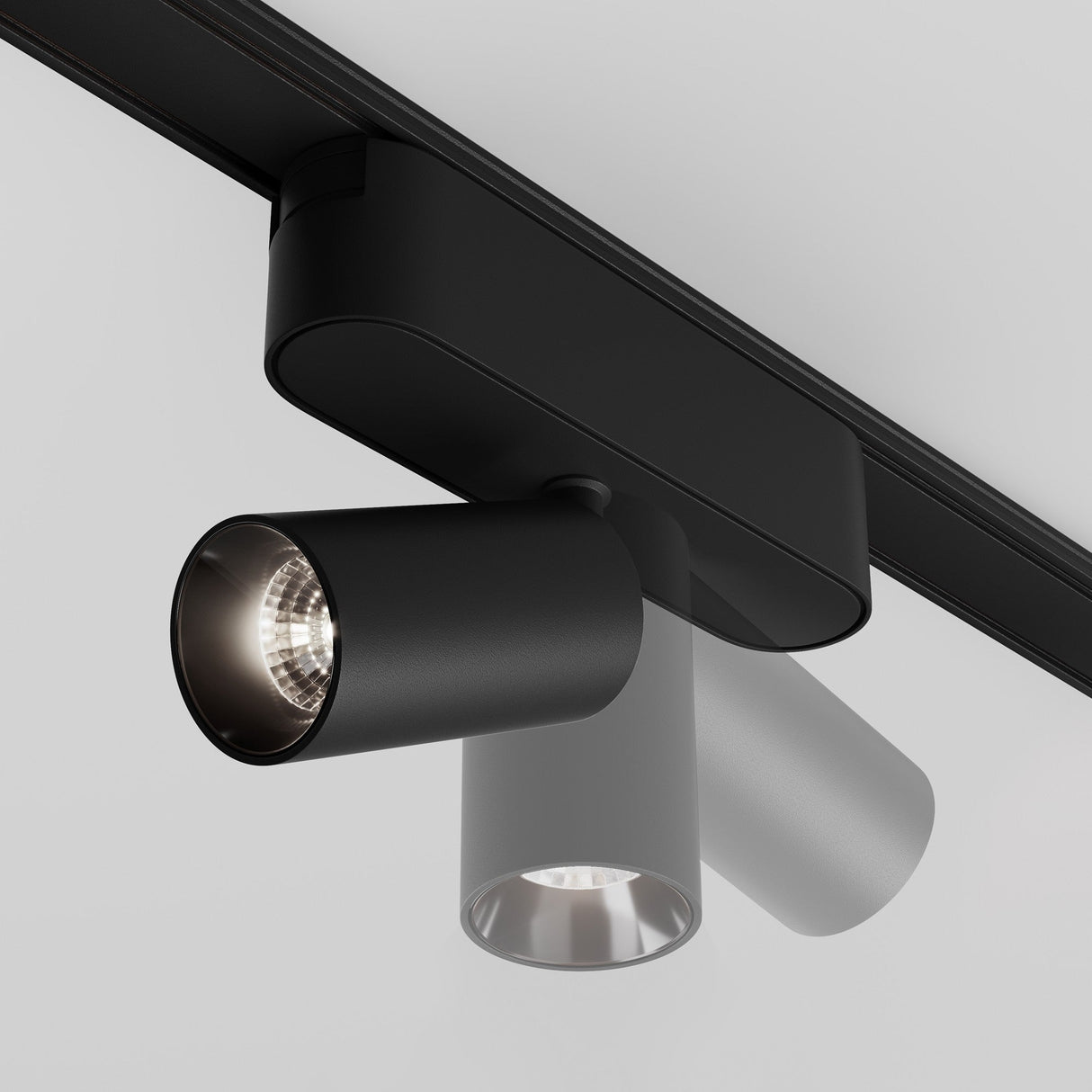 The Focus LED Magnetic Radity Track Spotlight 5W 4000K - Black is mounted on the ceiling with cylindrical, adjustable heads. One spotlight illuminates brightly while the other remains off, offering a modern minimalist design ideal for contemporary lighting solutions.