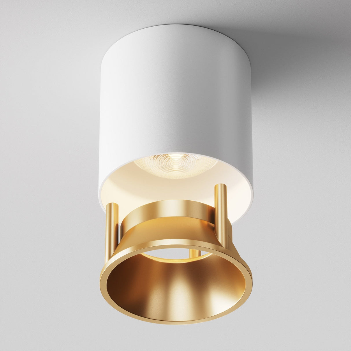 The Alfa LED Round Decorative Reflector Frame features a cylindrical white casing and matte gold ring detail, casting soft light and subtle shadows. This sleek, contemporary ceiling light is a perfect decorative addition when mounted on a white ceiling.