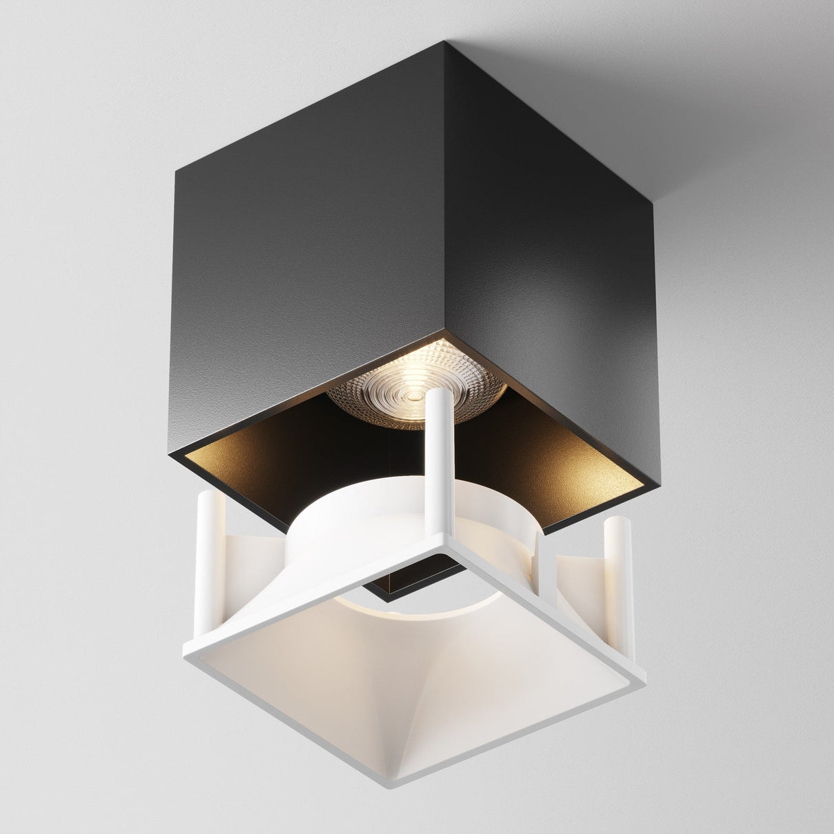 The Alfa LED Square Decorative Reflector Frame - White is a modern lighting fixture with a black cube design and an open bottom revealing a white circular element. Its minimalist style casts a warm glow, creating a stylish geometric look ideal for contemporary spaces.