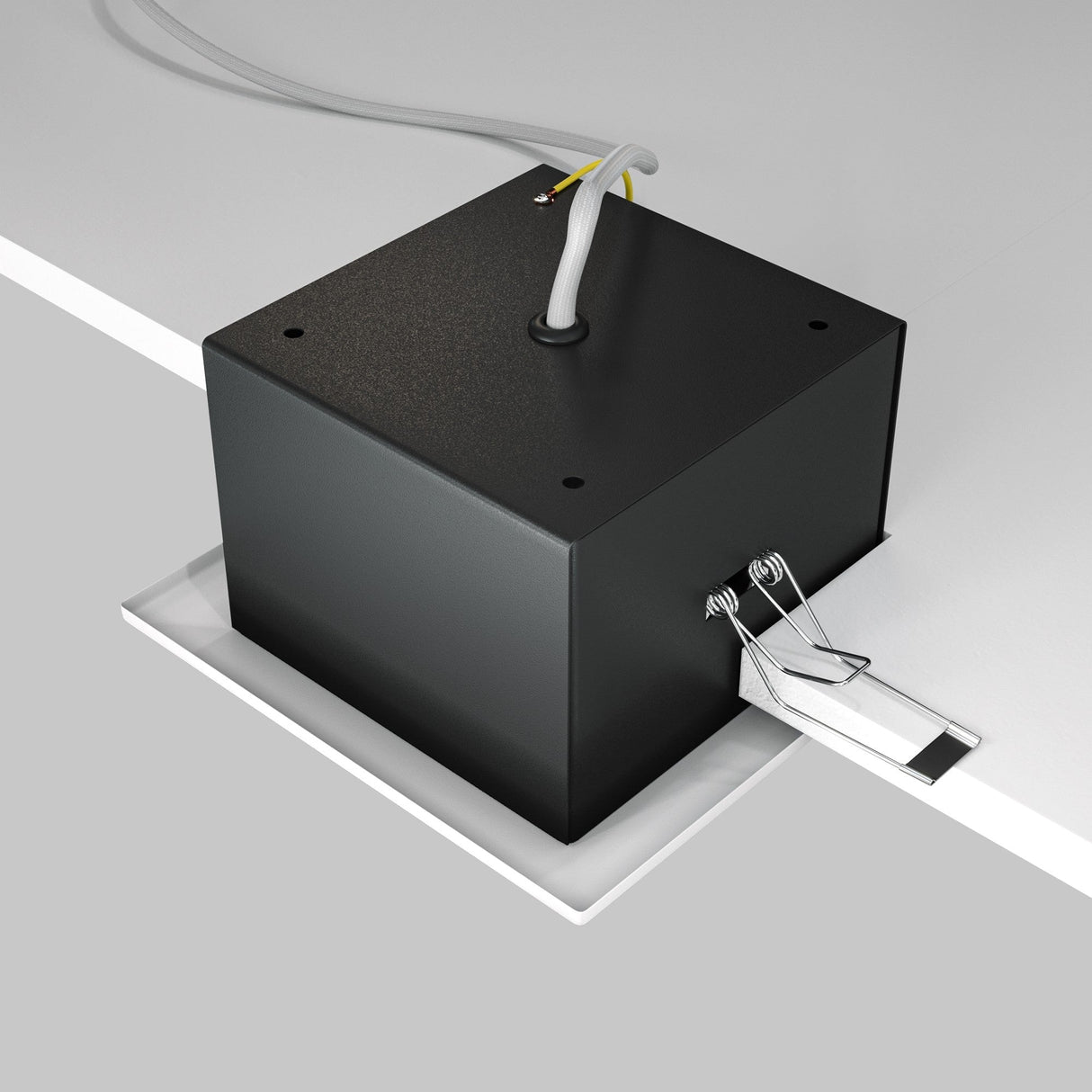 The Metal Modern Single Tilt Square Recessed Downlight - White, resembling a sleek black box with wires on a flat surface, incorporates two metal clips attached to a white rectangular section, perfect for table or panel installation.