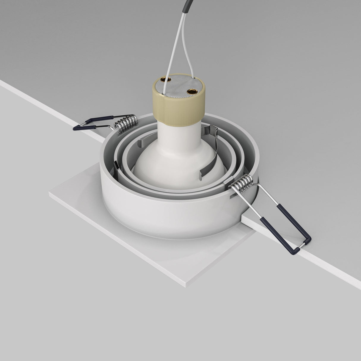 The Atom Single Tilt Square Recessed Downlight - White features a bulb socket, metal clips, and wires visible above its white base. It is shown partially installed in a ceiling against a gray background.