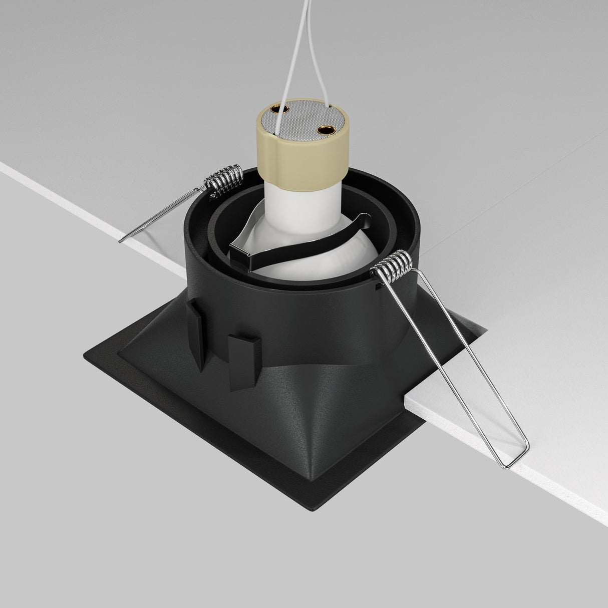 The Dot Single Tilt Square Recessed Downlight - Black is partially installed in a white ceiling, featuring a minimalist design with a sleek black finish, metal springs on the sides, and a beige socket at the top connected to wires.