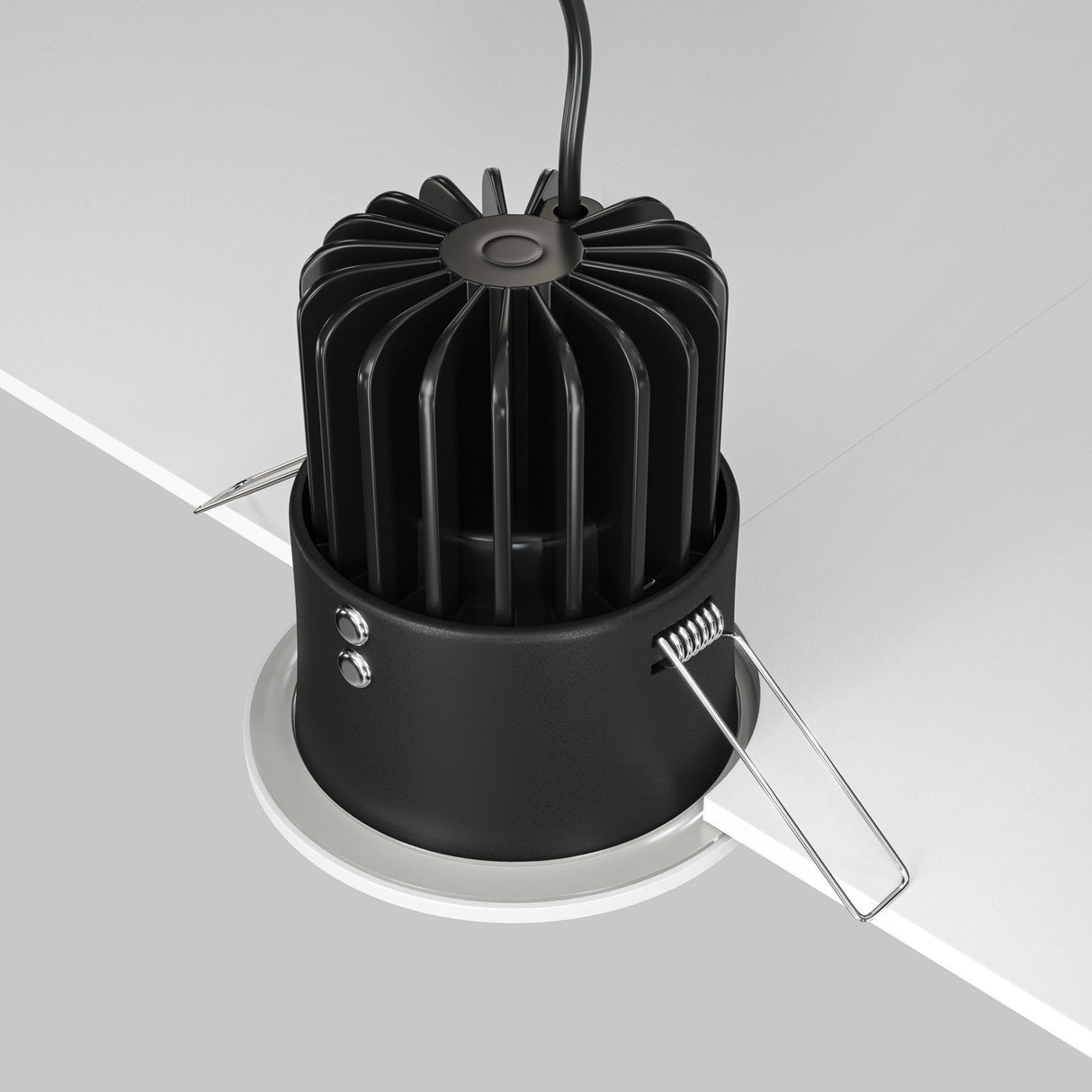 The Zoom LED Dimmable Round Recessed Downlight 12W 3000K - White is partially installed in a ceiling. This black downlight has a finned heat sink and metal spring clips for secure fitting, with an IP65 rating for durability. A power cable extends from the top.