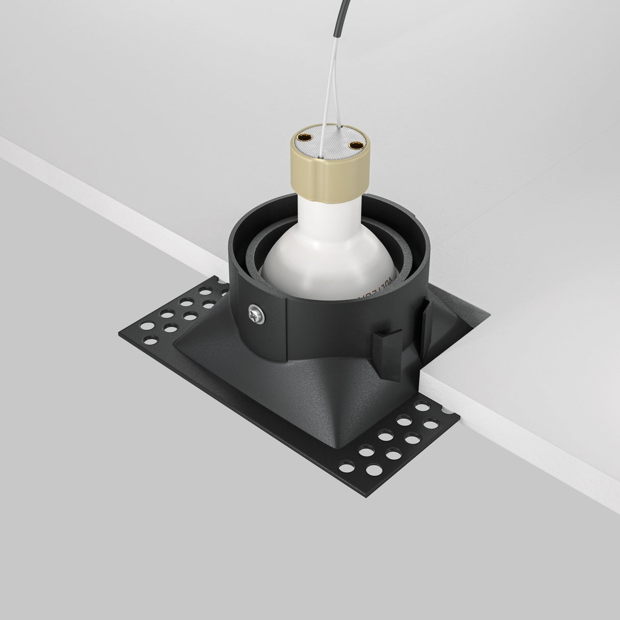 The Dot Single Tilt Square Plaster-in Recessed Downlight - Black features an adjustable tilt downlight with a partially embedded light fixture in white, surrounded by black housing and a gold cap. An energy-efficient cable extends upward, secured by a black bracket.