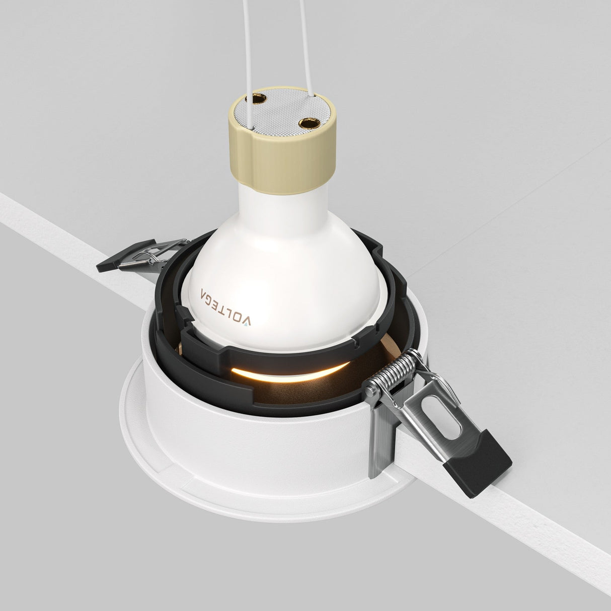 The Share Round Recessed Swivel Downlight in white and matte gold by VOLTEGA is partially embedded in a gray surface, featuring visible cords. It has metal clips for installation and offers an adjustable light fixture that elegantly enhances any space.