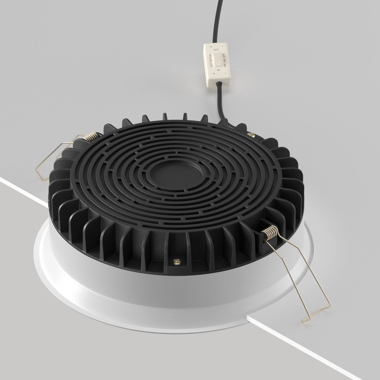 The Okno CCT LED Round Recessed Downlight 24W (3000-6000K) in black, partially installed in a white ceiling, features a ribbed design with metallic clips and an electrical wire for adjustable color temperature, offering an energy-efficient lighting solution.