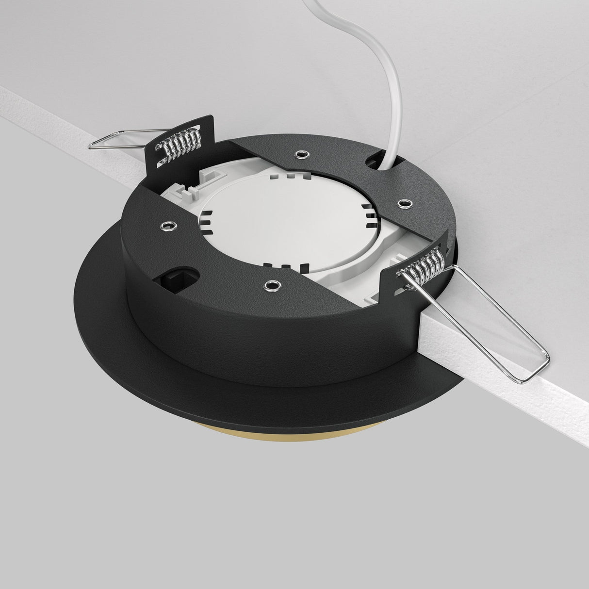 This close-up features the Hoop Single Fixed Round Recessed Downlight - Black & Gold, partially mounted in a white ceiling panel, with exposed metal clips, a wire, and an energy-efficient LED illuminating its circular structure and attachment mechanism.