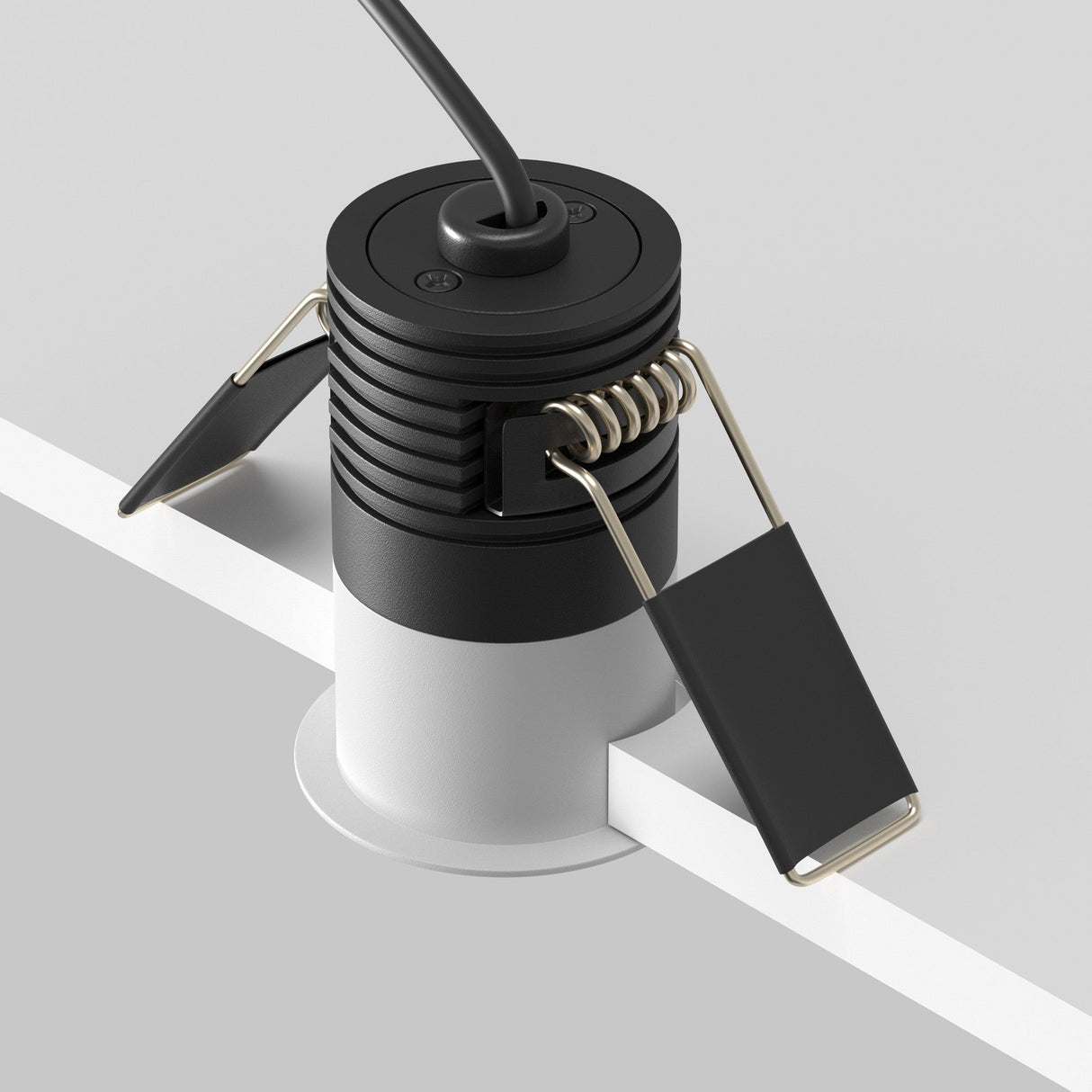 The Minor LED Recessed Downlight 5W 3000K - White & Black fits a sleek gray cutout with adjustable metal clips, showcasing its minimalistic design. An energy-efficient fixture, it includes a black cable extending from the top.