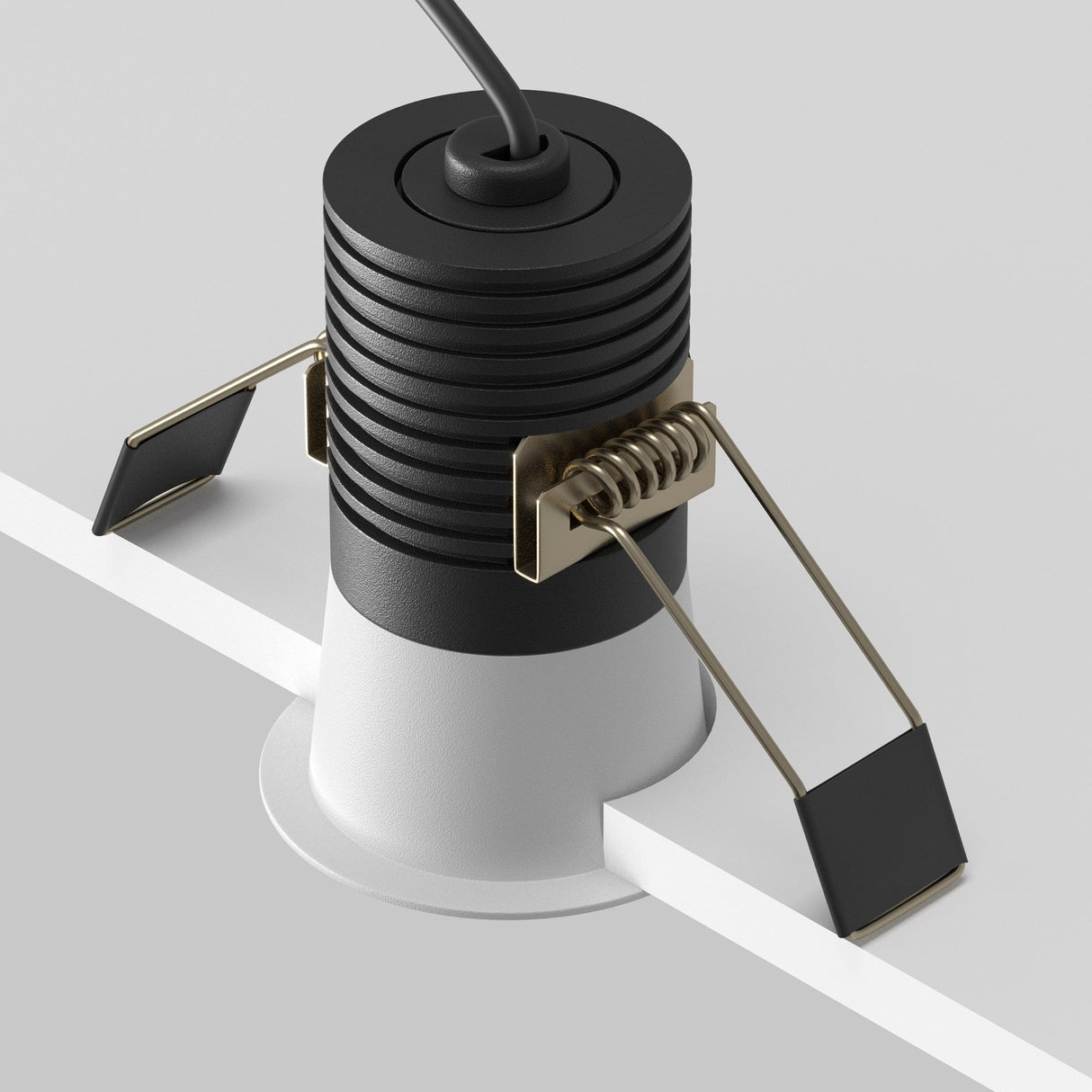 The Minor LED Recessed Downlight 9W 3000K, featuring a sleek black top and ribbed surface, is securely clamped onto a white surface with modern extended metal arms. An energy-efficient cable extends from the top.