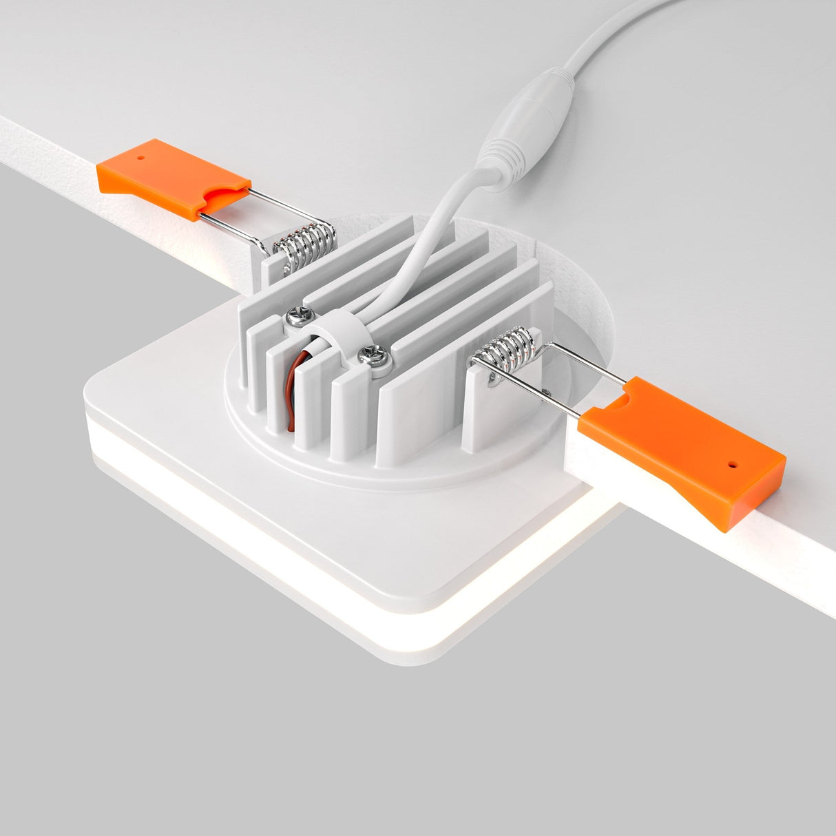 Close-up of the Phanton LED Recessed Downlight 7W 3000K in white, highlighting its energy-efficient LED technology. It has a round base with heat sink fins, a power cable, and spring-loaded clips with orange grips for secure ceiling installation.