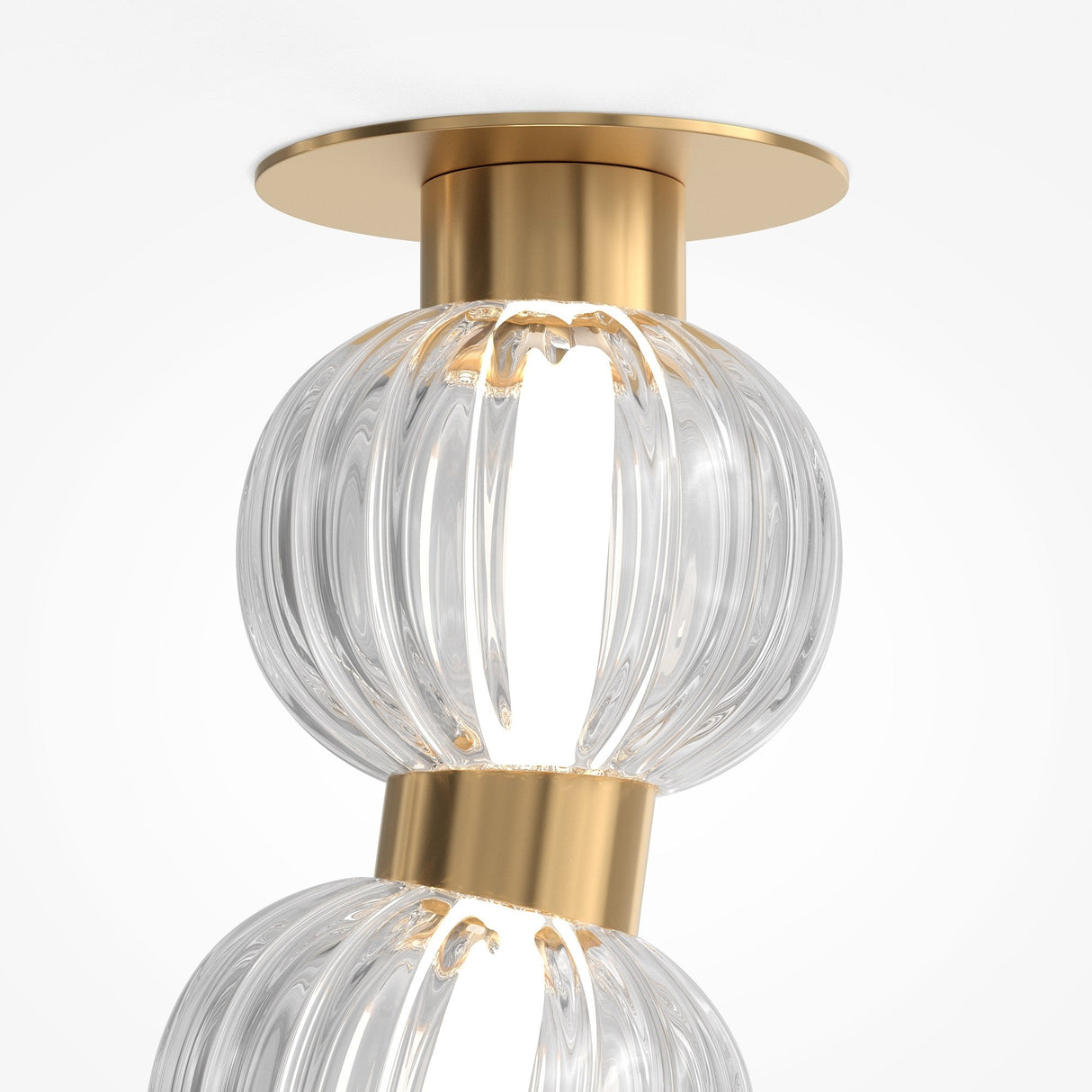 The Amulet LED Ceiling Light in gold showcases two vertically stacked, clear ribbed glass spheres with elegant metal accents against a white backdrop.