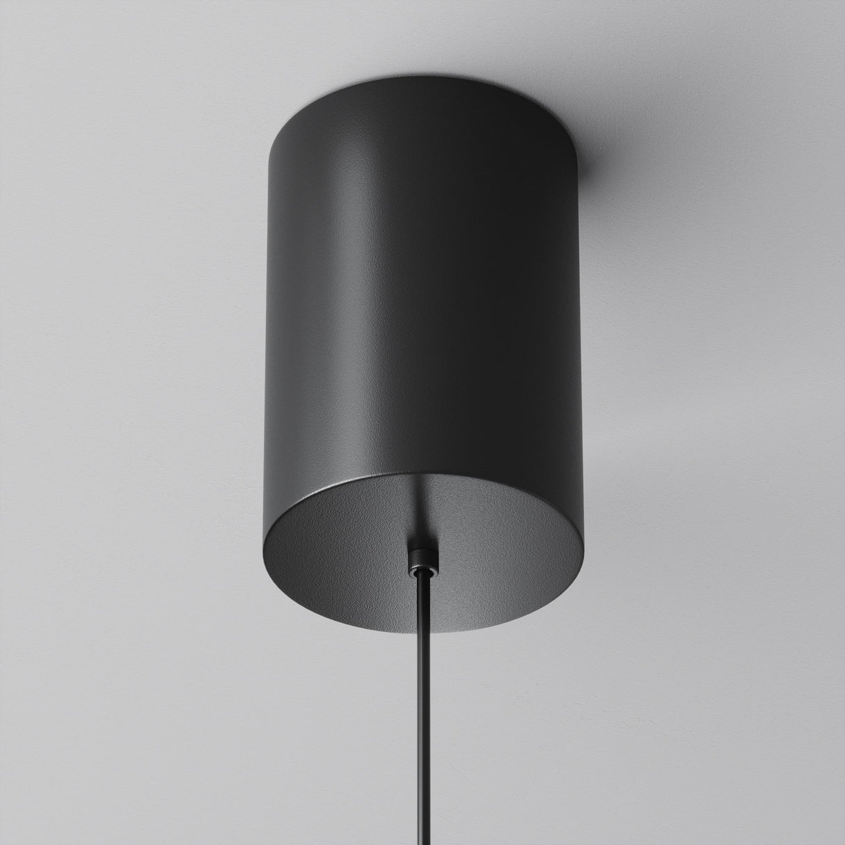 The Plato LED Pendant Light - Black features a cord-hung, black cylindrical design against a white ceiling. Its minimalist matte finish suits modern interiors, and its LED technology ensures energy-efficient style and sustainability.