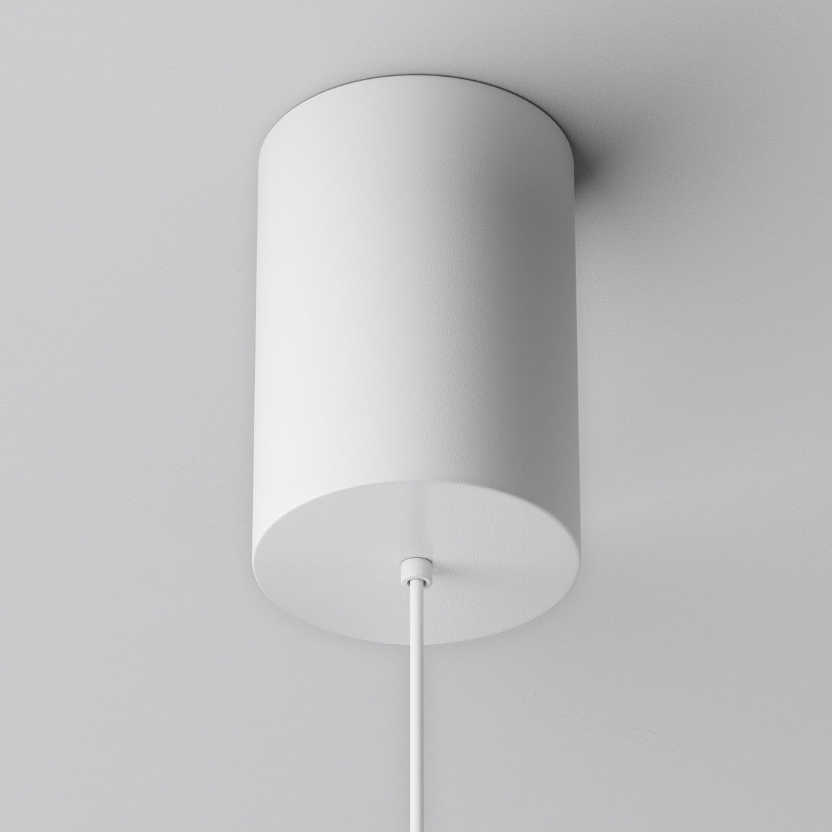 The Plato LED Pendant Light - White is a cylindrical ceiling fixture with energy-efficient LED technology. It features a minimalist design against a smooth white ceiling, with a power cord extending from its bottom to complement its modern aesthetic.