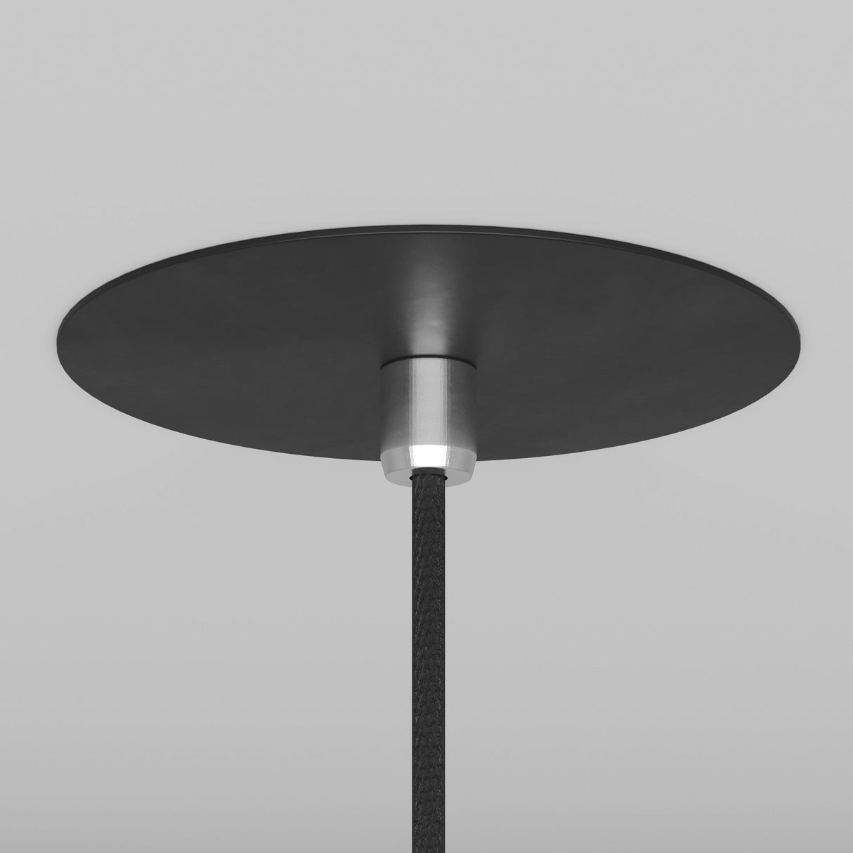 A close-up of the Nevill Conical Pendant Light - Black shows its round black base, metal connector, and braided black cord that enhance its minimalist design in a matte black finish against a white ceiling.