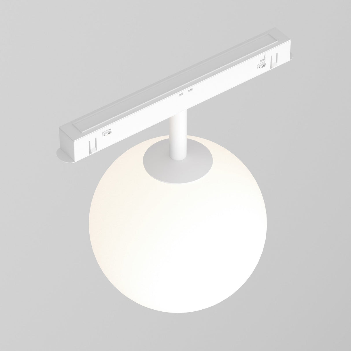 A Luna LED Magnetic Exility Track Globe Ceiling Light 5W 4000K - White emits a soft, warm glow from a spherical bulb attached to a white rectangular ceiling fixture against a light gray background, enhancing the modern minimalist aesthetic.