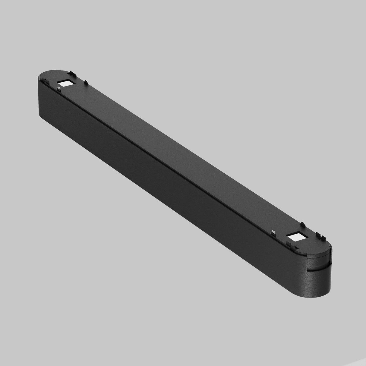 A long, black rectangular Basis LED Linear Track Light with rounded ends and small square cutouts rests against a gray background.