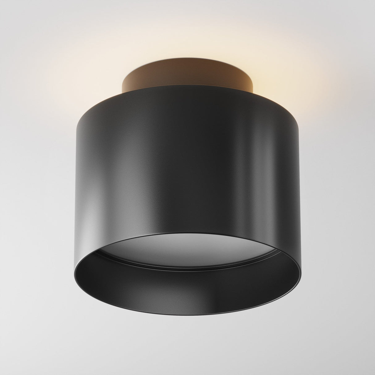The Planet LED Small Round Surface Downlight 3000K in black features a cylindrical design with a gold-toned base, casting a soft ambient glow on the white ceiling that exemplifies modern lighting aesthetics.