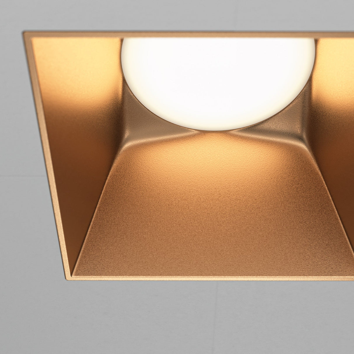 Close-up of Share square plaster-in fixed recessed downlight in matte gold, emphasizing its luxurious finish.